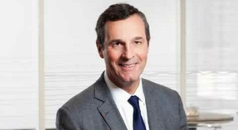 Portrait d’un homme souriant en costume-cravate dans un bureau lumineux, représentant un cadre dirigeant ou un expert institutionnel.