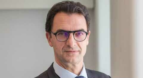 Portrait d’un homme en costume-cravate et lunettes, devant un fond clair de bureau, illustrant un cadre ou un responsable professionnel.