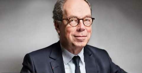 Portrait d’un homme en costume et cravate, assis devant un fond neutre, illustrant un profil de dirigeant ou d’expert.